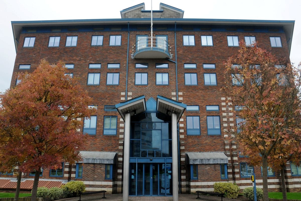 Modern brick office building with blue entrance and autumn trees